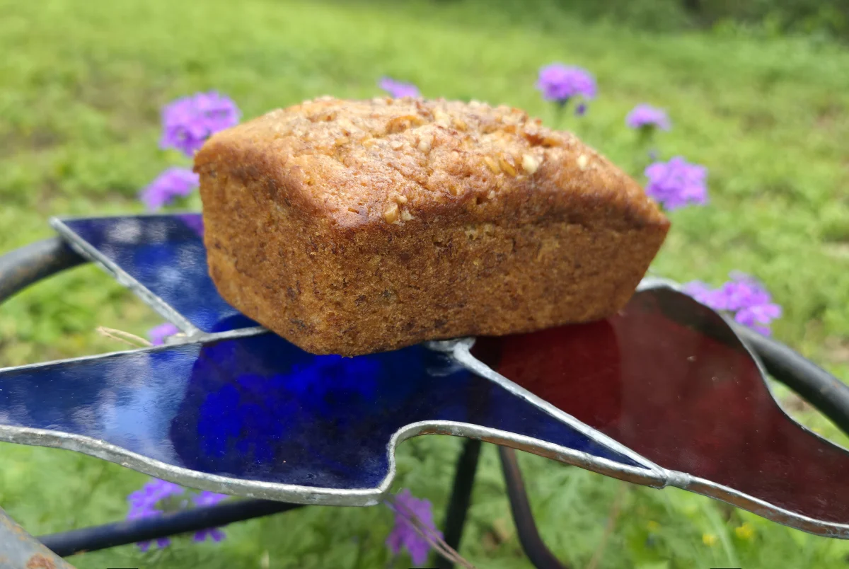A Signature Banana loaf on a stained-glass stand among purple wildflowers